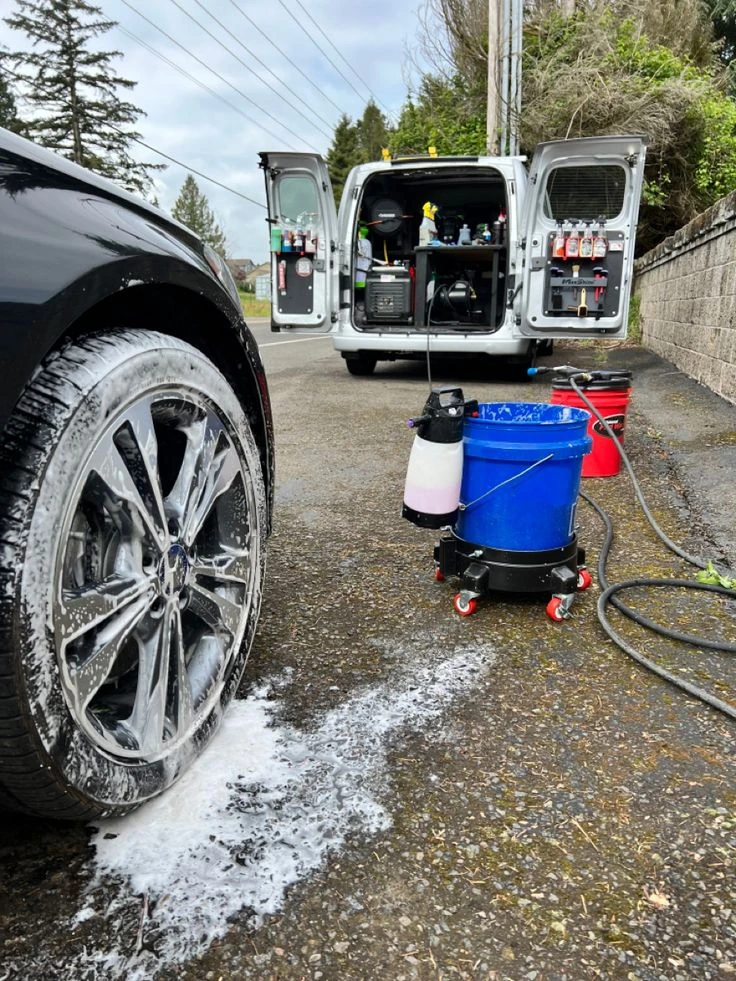 Wheel cleaning tools beside a mobile detailing van